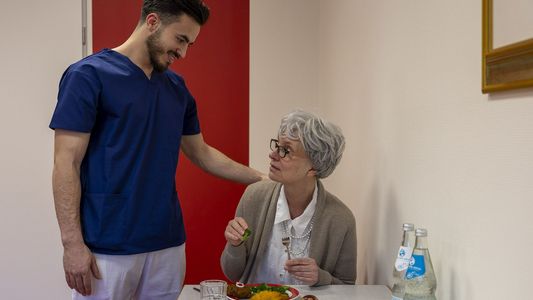 Pflegeschüler assistiert Demenzkranker beim Essen